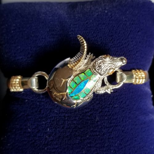 Close-up of a dragon-shaped bracelet with iridescent scales on a dark fabric background.