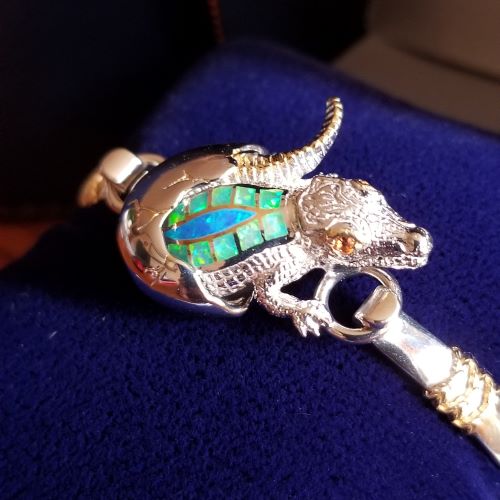 Close-up of a silver lizard-shaped brooch with colorful inlays.