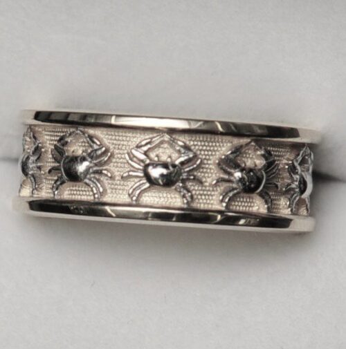 Silver ring with crab engravings and intricate patterns.