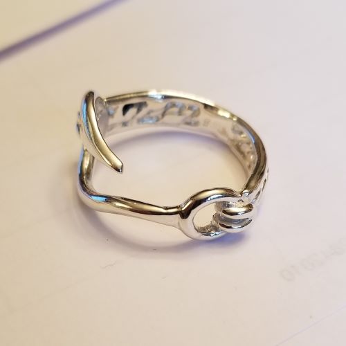 Silver ring shaped like a hand holding a rod.
