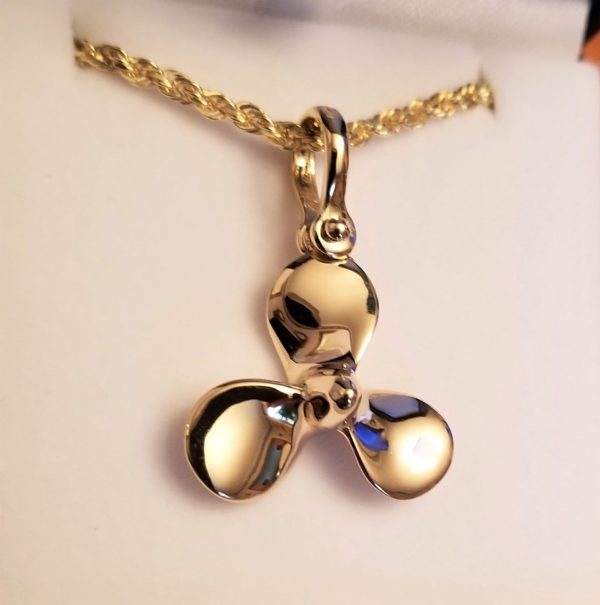 Gold pendant shaped like a propeller on a chain.