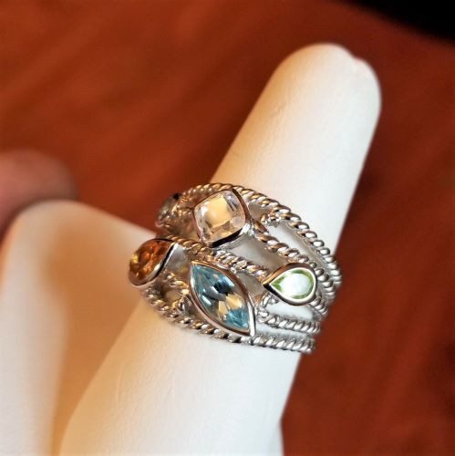 Silver ring with multiple gemstones on a display stand.