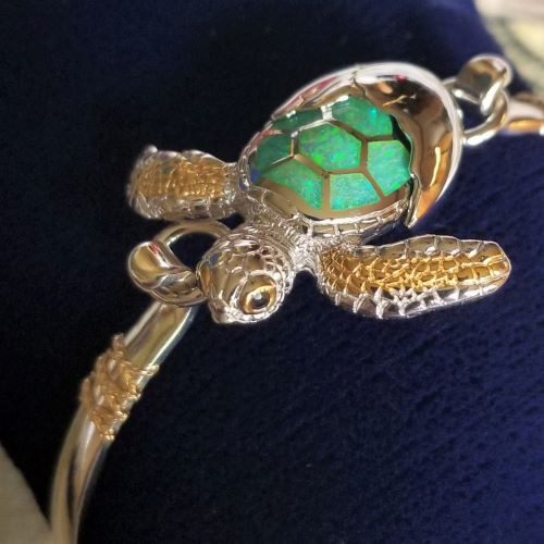 Close-up of a turtle-shaped bracelet with a green shell on a dark background.