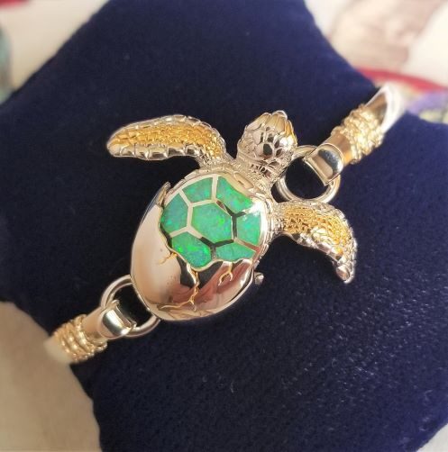 Gold turtle-shaped bracelet with green shell detail.