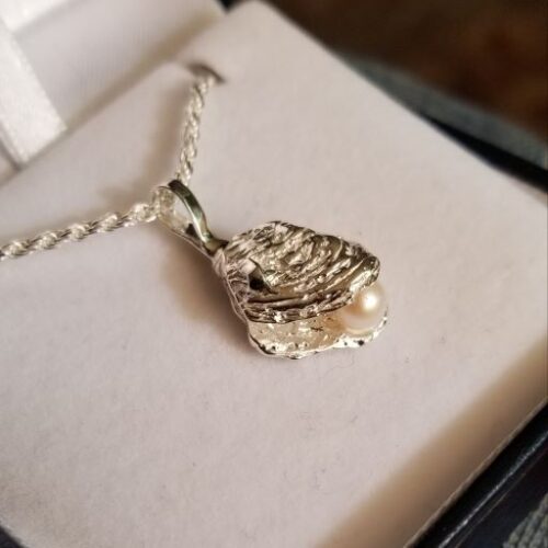 Silver pendant shaped like praying hands on a chain.