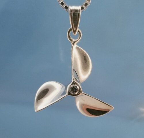 Close-up of a silver pendant with three curved blades on a chain.