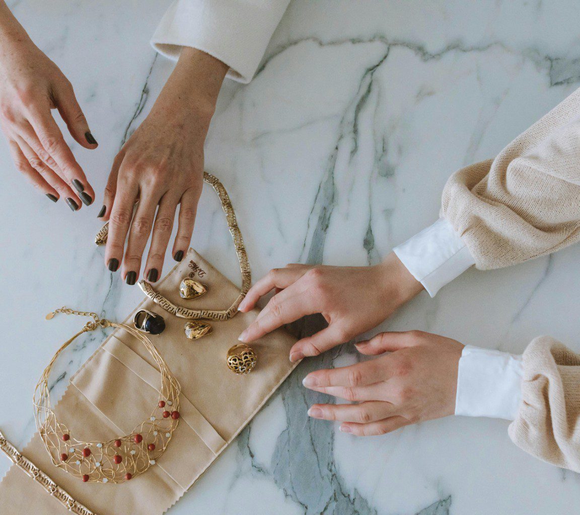 Two people sharing a wooden board with dried fruits and nuts on a marble table.