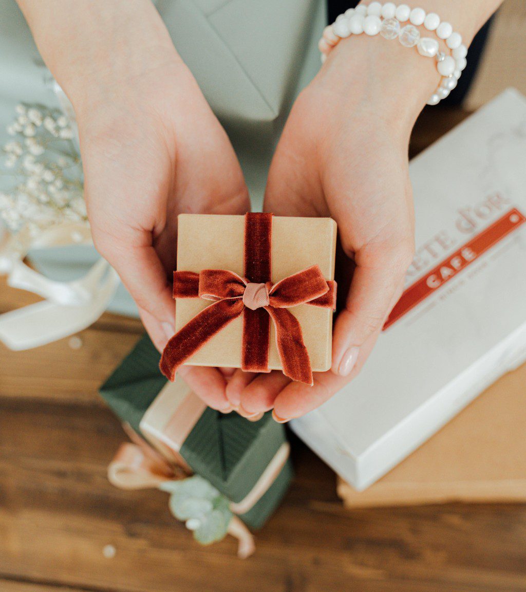 Hands holding a small, wrapped gift with a red ribbon.