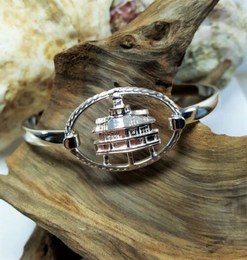 Silver bracelet with a detailed globe charm on a wooden surface.