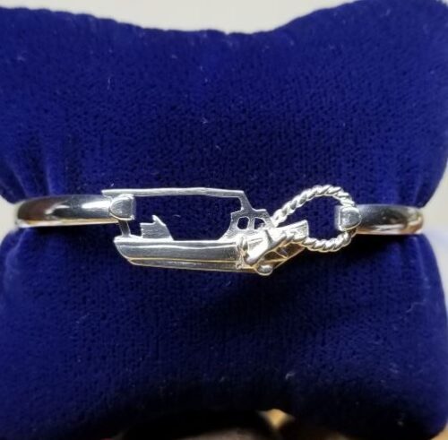 Silver bracelet with a boat and rope design on a blue cushion.