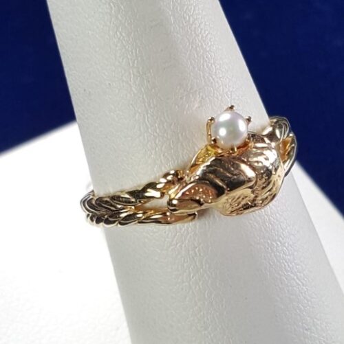Gold ring with pearl on display stand.